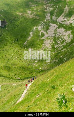 Blick auf eine Gruppe von Wanderern auf ihrem Weg nach Le Reculet, die wie winzige Punkte in der massiven Weite der Jura-Berglandschaft aussieht Stockfoto