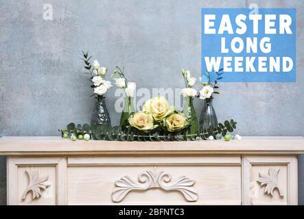 Text OSTERN LANGES WOCHENENDE im Hintergrund. Florale Komposition auf Holzmantelstück Stockfoto