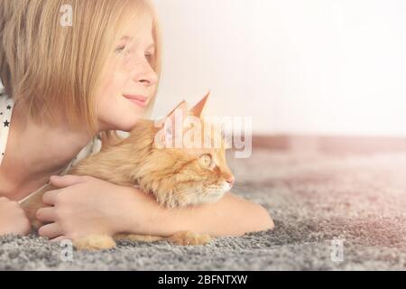 Teenager-Mädchen mit niedlichen Katze auf dem Boden zu Hause liegen Stockfoto