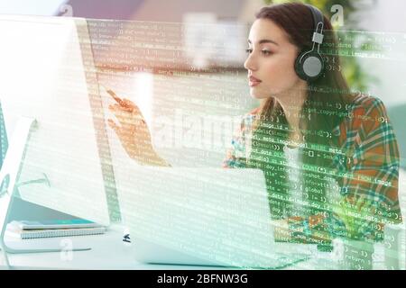 Konzept der Programmentwicklung. Junge Frau, die Musik hört, während sie mit dem Computer arbeitet Stockfoto