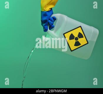 Konzept der Umweltverschmutzung. Hand Gießen giftiges Wasser aus Dose vor Farbhintergrund Stockfoto
