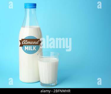 Flasche und Glas Mandelmilch auf blauem Hintergrund Stockfoto