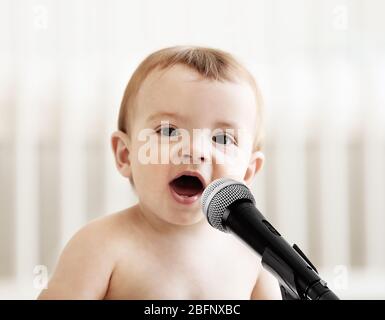 Niedliches Baby mit Mikrofon auf hellem Hintergrund Stockfoto