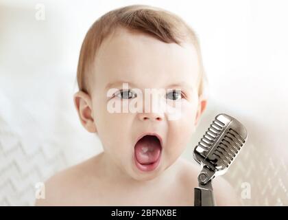 Niedliches Baby mit Mikrofon auf hellem Hintergrund Stockfoto