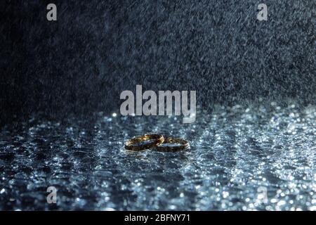 Beziehungstests. Zwei goldene Eheringe liegen in Tropfen blauen Wassers. Stockfoto