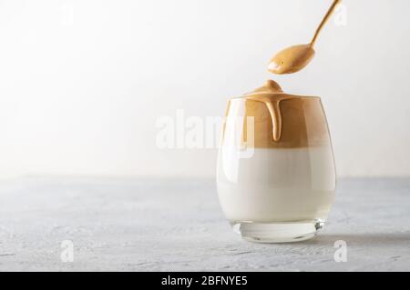 Koreanischer Drink Dalgona Kaffee im Glas mit Milch und Instant-Kaffee auf weißem Hintergrund. Kopierbereich. Stockfoto