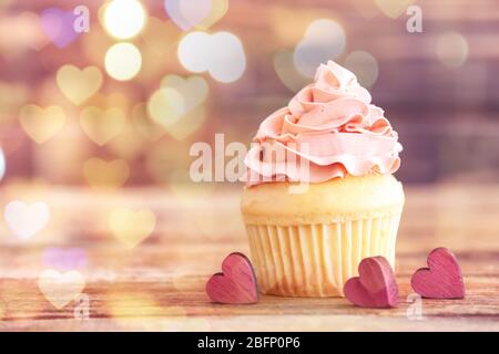 Leckere Cupcake mit verschwommenen Lichtern auf farbigem Hintergrund Stockfoto