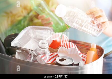 Frau wirft Müll in Mülltonne, Nahaufnahme. Recyclingkonzept Stockfoto