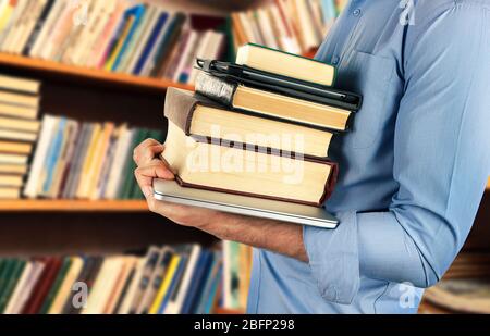 Student hält Bücher und Laptop in der Bibliothek Stockfoto