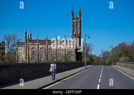 Covid-19 Lockdown, eine junge Frau geht über eine verlassene Dean Bridge mit der Rhema Kirche im Hintergrund. Edinburgh, Schottland, Großbritannien Stockfoto