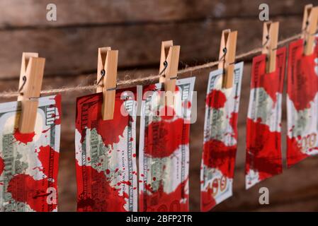 Konzept der Geldwäsche - Dollar mit Blutflecken trocknen auf Schnur auf Holzhintergrund, Nahaufnahme Stockfoto