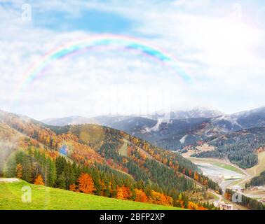 Schöne Berg Herbstlandschaft mit grünem Gras auf Wiese nach Regen mit Regenbogen Stockfoto