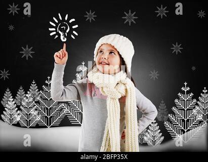 Kleines Mädchen in einem trendigen gestrickten Kleidung suchen und gezogen Winterwald auf Tafel Hintergrund Stockfoto