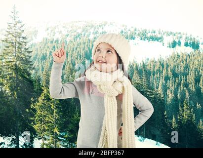 Kleines Mädchen in einem trendigen gestrickte Kleidung suchen auf Winter Wald Hintergrund Stockfoto