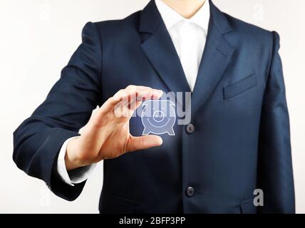 Geschäftsmann hält virtuelle Sparschwein auf hellem Hintergrund Stockfoto