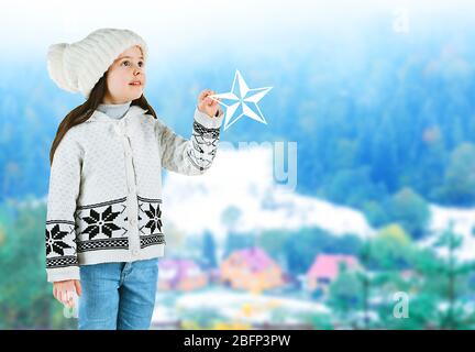 Kleines Mädchen in einem trendigen Stricksachen auf verschwommenem Landschaftshintergrund Stockfoto