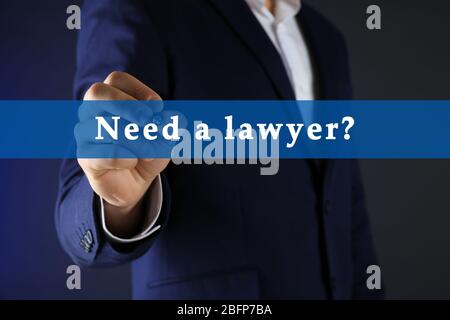 Geschäftsmann im Anzug mit Stift auf dunklem Hintergrund. Brauchen Sie einen Anwalt? Stockfoto