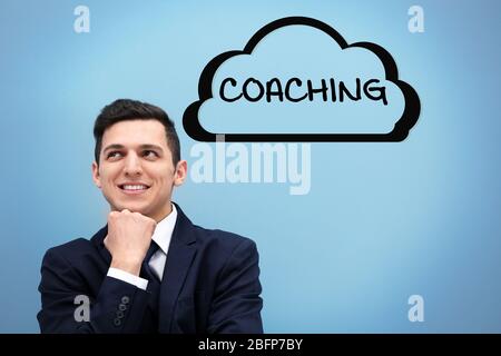 Konzept des persönlichen Coachings. Attraktiver junger Mann im Anzug gegen hellblaue Wand Stockfoto