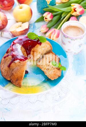 Torte mit rotem Tüpfelchen auf einem hellen Hintergrund und einem Strauß Tulpen. Frühlingsfrühstück Stockfoto