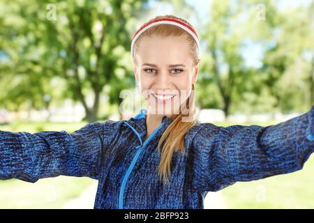 Schöne sportliche Frau, die Selfie auf verschwommenem Naturhintergrund nimmt. Sportkonzept. Stockfoto