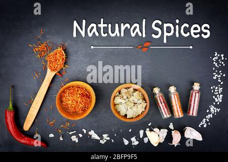 Zusammensetzung von verschiedenen Gewürzen auf dunklem Hintergrund. Text Natürliche Gewürze. Stockfoto