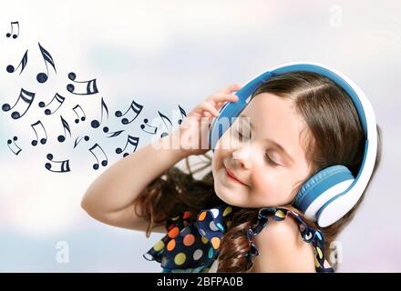 Kleines nettes Mädchen, das Musik hört. Musikalische Notizen Design auf hellem Hintergrund. Stockfoto