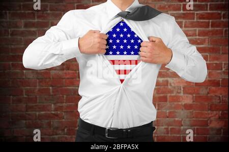 Geschäftsmann zeigt USA Flagge unter Anzug auf Backstein Wand Hintergrund. Stockfoto