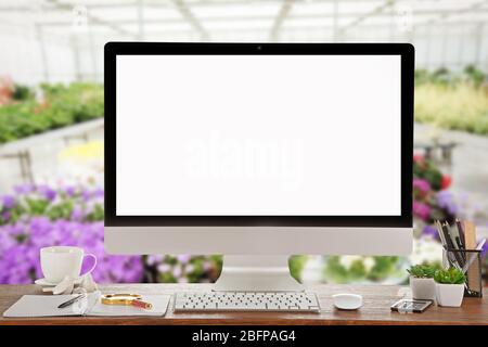 Computer mit leerem Bildschirm auf Blumenshop Hintergrund Stockfoto