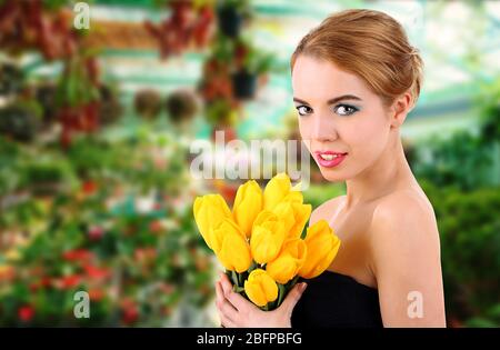 Junge Frau mit schönen Blumenstrauß Tulpen auf Blumengeschäft Hintergrund Stockfoto