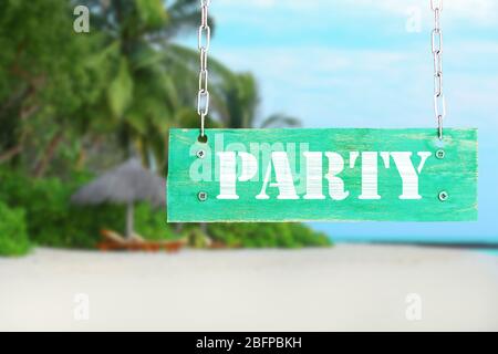 Holzschild mit Text PARTY auf tropischen Strand und blauen Himmel Hintergrund Stockfoto