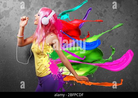 Junge Frau, die Musik in Kopfhörern hört. Buntes Design auf dunklem Hintergrund. Stockfoto