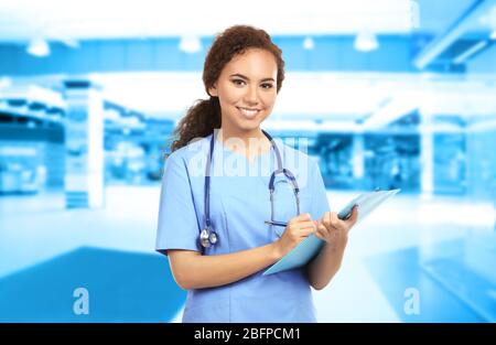 Junger Arzt auf verschwommenem Krankenhaushintergrund. Konzept für medizinische Versorgung. Stockfoto