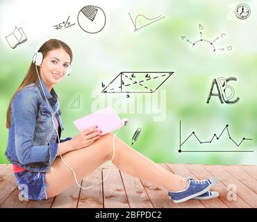 Junge Frau mit Buch sitzt auf Holzboden und hört Musik vor verschwommenem Hintergrund. Vielfalt der Schule Ikonen auf Hintergrund. Stockfoto