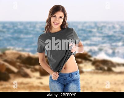 Junge Frau in stilvollem T-Shirt auf Landschaftshintergrund Stockfoto