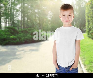 Kleiner Junge in stilvollem T-Shirt auf Landschaftshintergrund Stockfoto