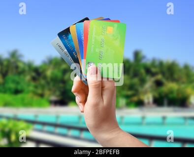 Reisekonzept. Frau mit Kreditkarten und Resort im Hintergrund Stockfoto