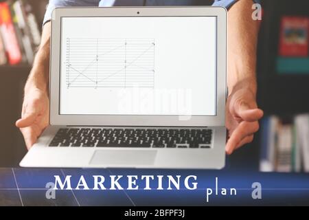 Konzept des Marketingplans. Mann, der den Laptop in den Händen hält Stockfoto