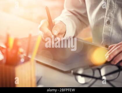 Designkonzept. Mann, der mit einem Grafiktablett am Tisch arbeitet, Nahaufnahme Stockfoto