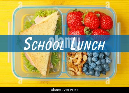 Konzept des Schulmahls. Lunchbox und Essen auf Holzhintergrund Stockfoto