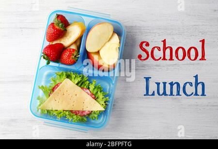 Konzept des Schulmahls. Lunchbox und Essen auf Holzhintergrund Stockfoto