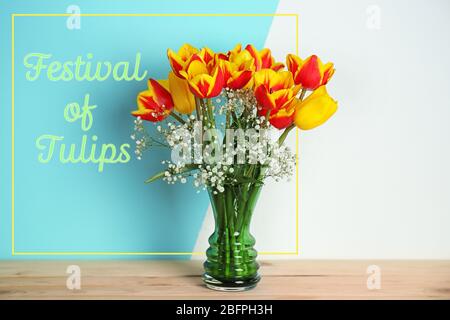 Text FESTIVAL VON TULPEN und schönen Blumen in Vase auf farbigen Hintergrund Stockfoto