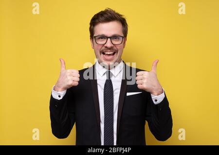 Reife kaukasischen Geschäftsmann mit Schnurrbart zeigt Daumen nach oben. studio auf rosa Wand gedreht. Stockfoto
