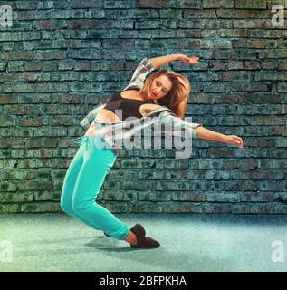 Junge Hip-Hop-Tänzerin auf Backstein-Wand Hintergrund Stockfoto