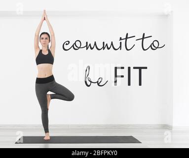 Fitness-Angebote. Text COMMIT FIT zu SEIN und junge Frau Yoga auf weißen Wand Hintergrund zu praktizieren Stockfoto