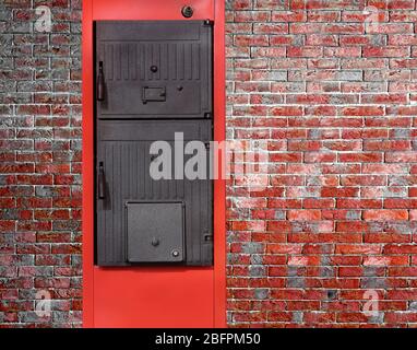 Energieeinsparkonzept. Festbrennstoffkessel auf Backsteinwand Stockfoto