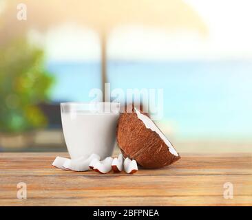 Ein Glas Kokosmilch mit Nuss auf einem Holztisch Stockfoto
