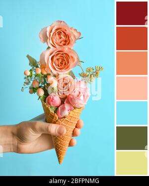 Palette mit Lachs Farbe und Frau hält Waffel Kegel mit floralen Komposition auf blauem Hintergrund Stockfoto