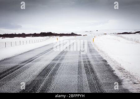 Die südliche Ringstraße mit dem Wind, der an einem windigen Tag in Island, Nordeuropa, Schnee über die Straße bläst Stockfoto