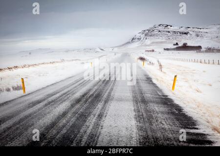 Die südliche Ringstraße mit dem Wind, der an einem windigen Tag in Island, Nordeuropa, Schnee über die Straße bläst Stockfoto