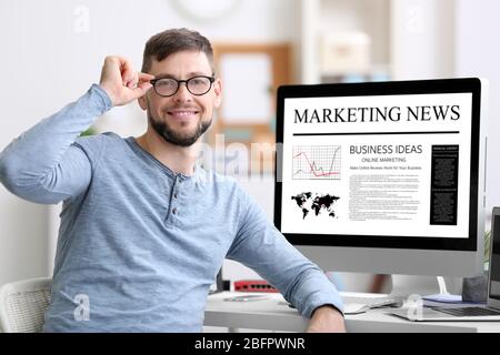 Mann, der im Büro arbeitet. Marketing-News auf dem Computerbildschirm Stockfoto